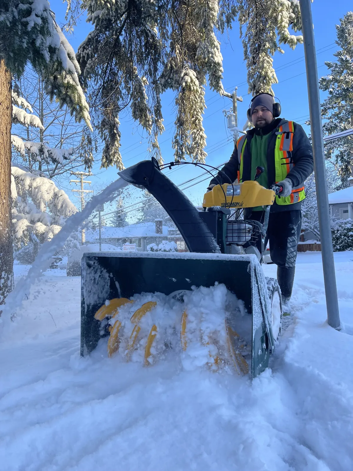 Crew member clearing snow with a snow blower in Burnaby