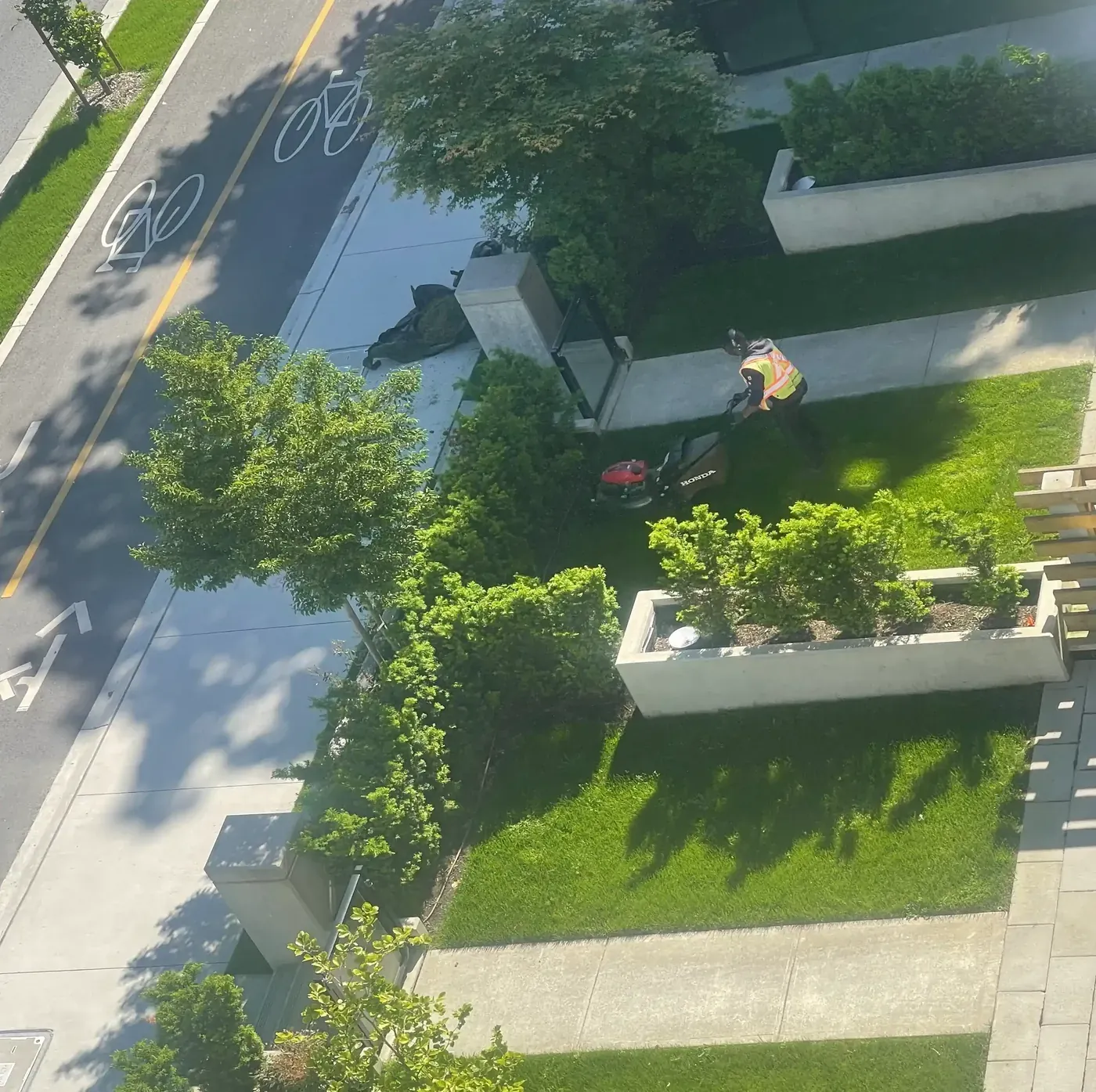 Tandem crew mowing a raised planter lawn at a strata property