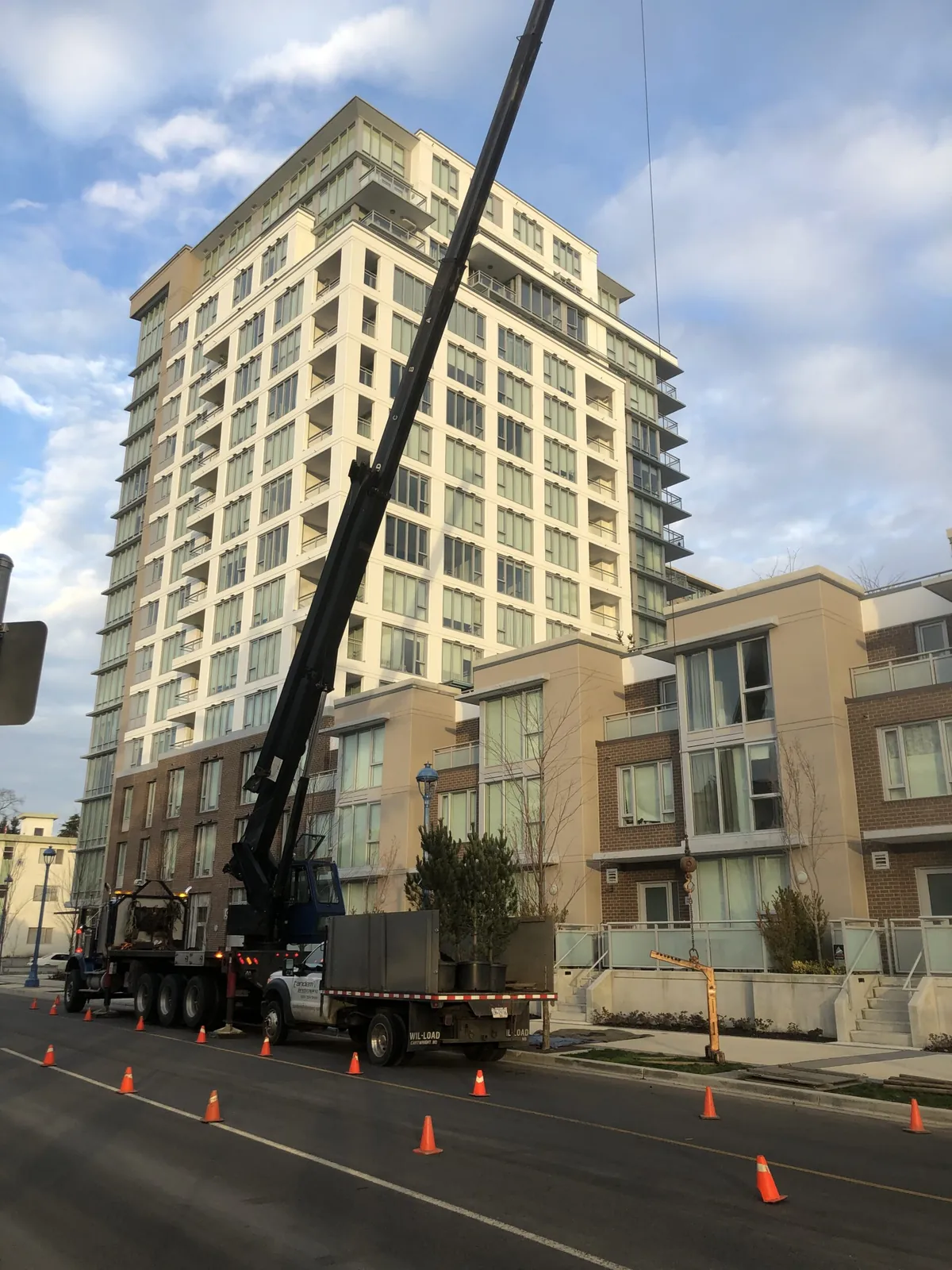 Crane truck planting trees beside a high-rise in Richmond