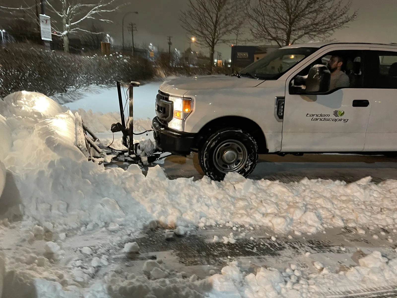 Tandem Landscaping truck plowing snow at night